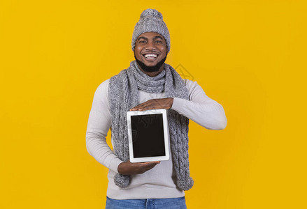 AfricanAmerican微笑的冬季男子显示空白数字平板屏幕黄图片