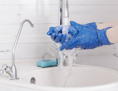 一名住宅清洁员戴着蓝色手套洗手图片
