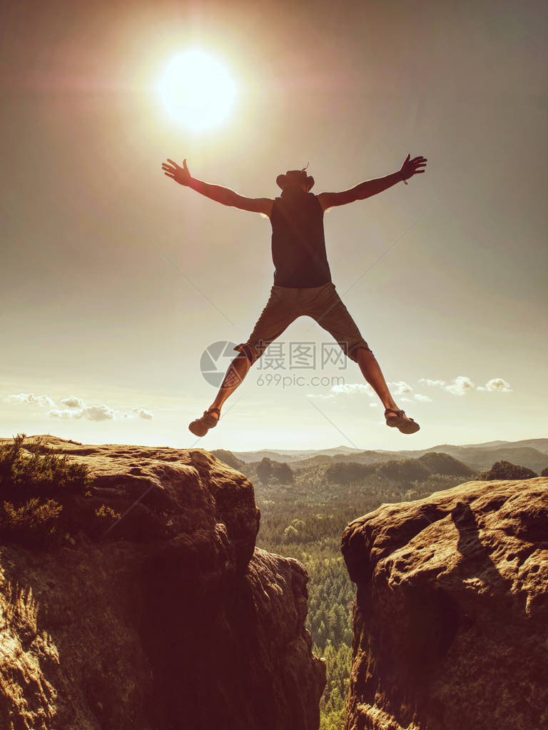 与太阳跳跃跳崖穿越山路的人积极的生活方式图片
