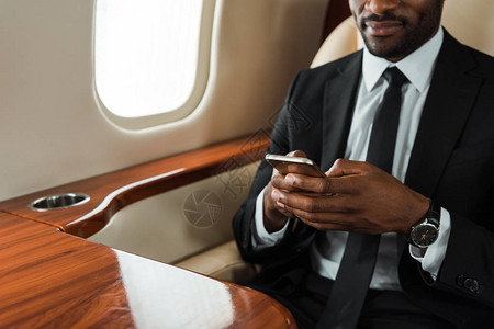 在私人喷气式飞机上使用智能手机的非洲裔美国图片