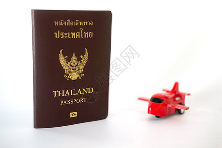 一本泰国公民护照和一个白色背景的小型红色飞机玩具图片
