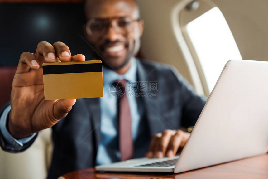 在私人飞机上持有笔记本电脑附近信用卡的非裔美国商人有选择图片