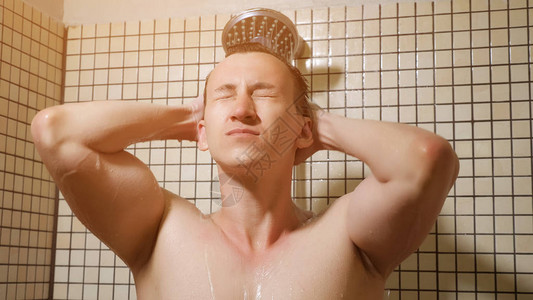 英俊的男人早上用雨水淋浴喷头洗澡的画像他站在水下图片