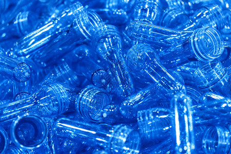 注射过程的预形堆积集装箱中的PET瓶子工厂内的塑料饮用水瓶制造过程背景图片