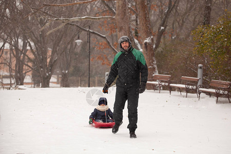 父亲拉着一个孩子在雪橇上父亲和儿图片