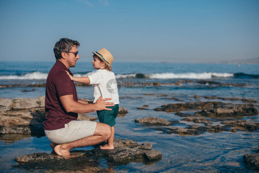 父亲带着一个小儿子在海边旅行图片