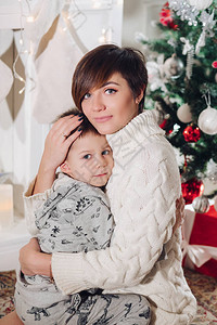 积极的小可爱男孩和漂亮的妈在装饰时尚的工作室拥抱圣诞假期图片