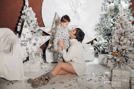 年轻快乐的父母在树上为小儿子展示圣诞装饰圣诞节灯光和时尚工作室的装饰图片