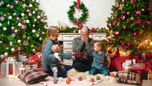 快乐成功的家庭坐在圣诞环境中交换礼物图片