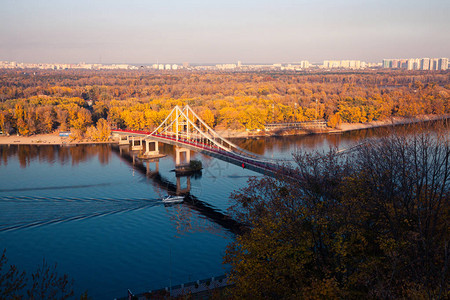 秋树和河上浮船背景下的河上散步桥图片