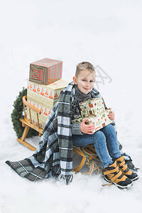 坐在装饰着礼物盒的木制雪橇上图片