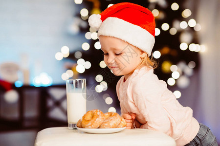 可爱的小女孩在圣诞树附近看圣诞老人的美食图片