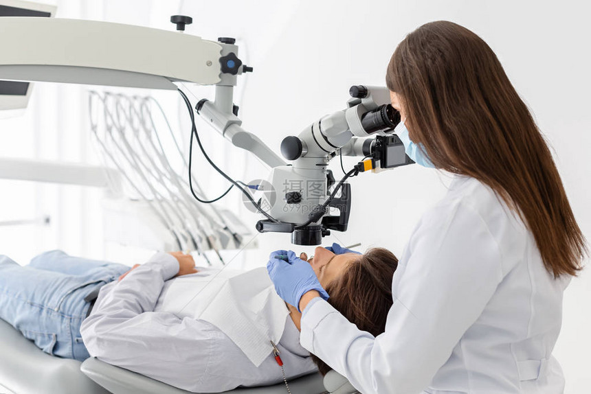 在牙科治疗中使用现代技术的专业女图片