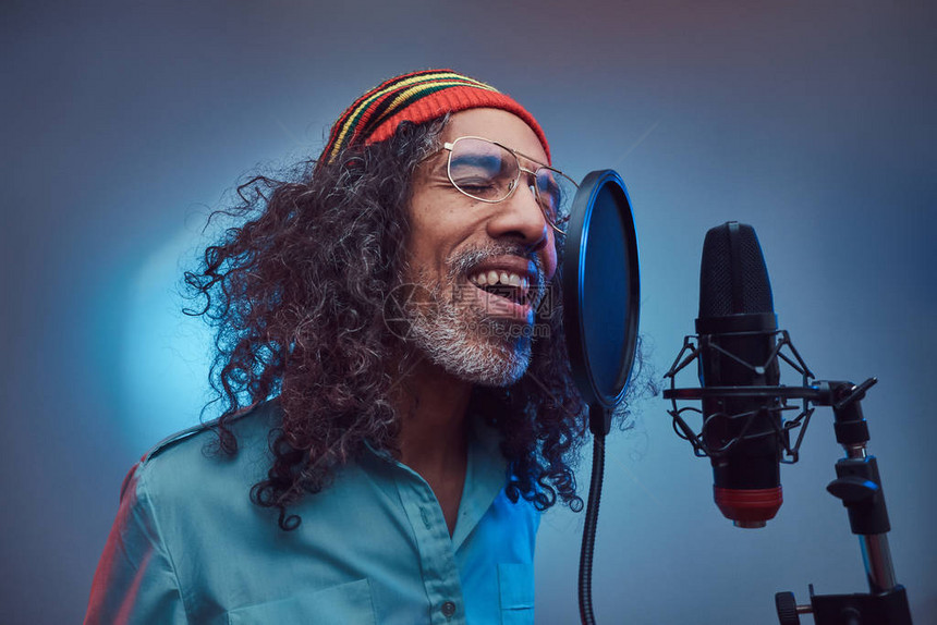 身着蓝衬衫的非洲Rastafarian男歌手在录音室写歌时也带着情感色彩图片