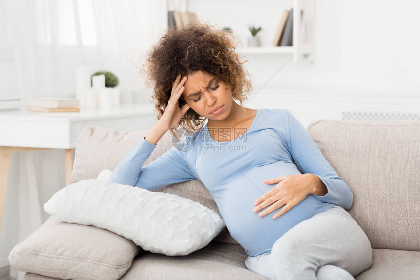 怀孕期间生病年轻孕妇在沙发上感到痛苦难图片