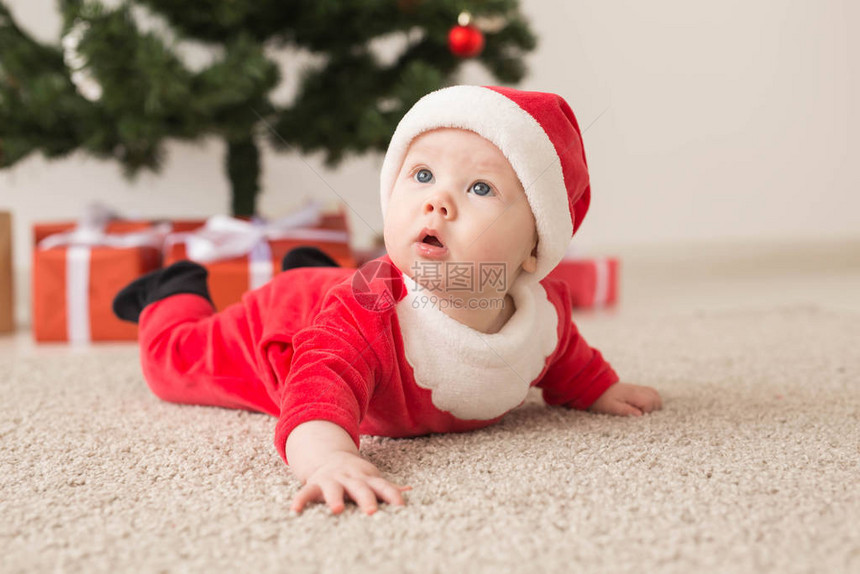 穿着圣达克萨斯西装的可爱女婴在圣诞树上地图片