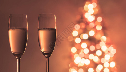 圣诞树旁边有两杯香槟杯子假日背图片