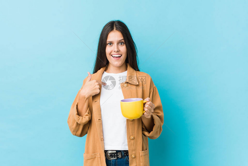 年轻caucasian女人拿着咖啡杯惊讶地指着自己图片