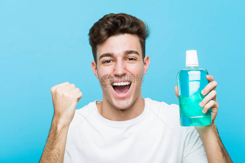 年轻的caucasian男子拿着一个口水洗的欢呼声图片