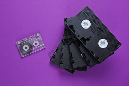 紫色背景上的一叠复古录像带和录音带顶视图图片