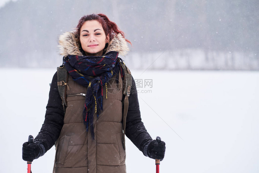 在白雪皑的森林旁徒步旅行的快乐红发女孩图片