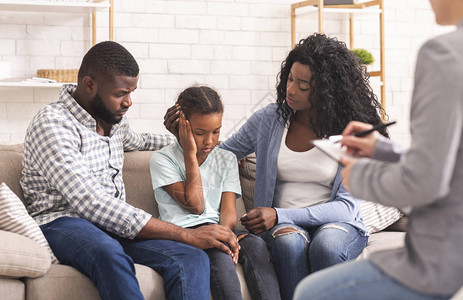 有爱心的非洲裔美国父母在心理学家咨询时抚慰他们心烦意乱的小女儿图片