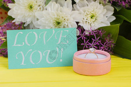 情人节的浪漫惊喜带金戒指鲜花和卡片的礼物盒在彩色背景上爱你图片