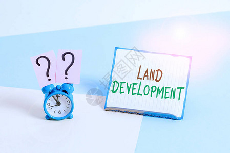 新大陆概念手写显示土地开发为建设基础设施获取土地的概念意义过程闹钟在一张纸片旁边放置在背景