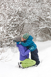 孩子拥抱妈一个男孩和他的母亲在冬天散步一个戴着针织帽的孩子亲吻他的母亲那个女人支持她的儿子母一家人一起度过时光背景图片