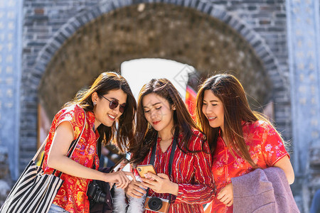 肖像三位亚洲幸福女在丽江古城旅行时一起使用智能手机进行社交网络图片