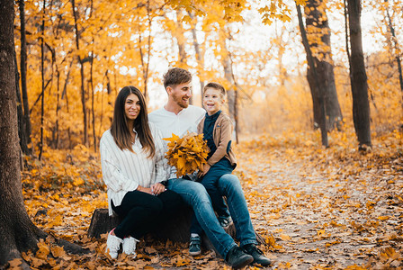 美丽的年轻快乐父母和小儿子在秋天公园共度时图片