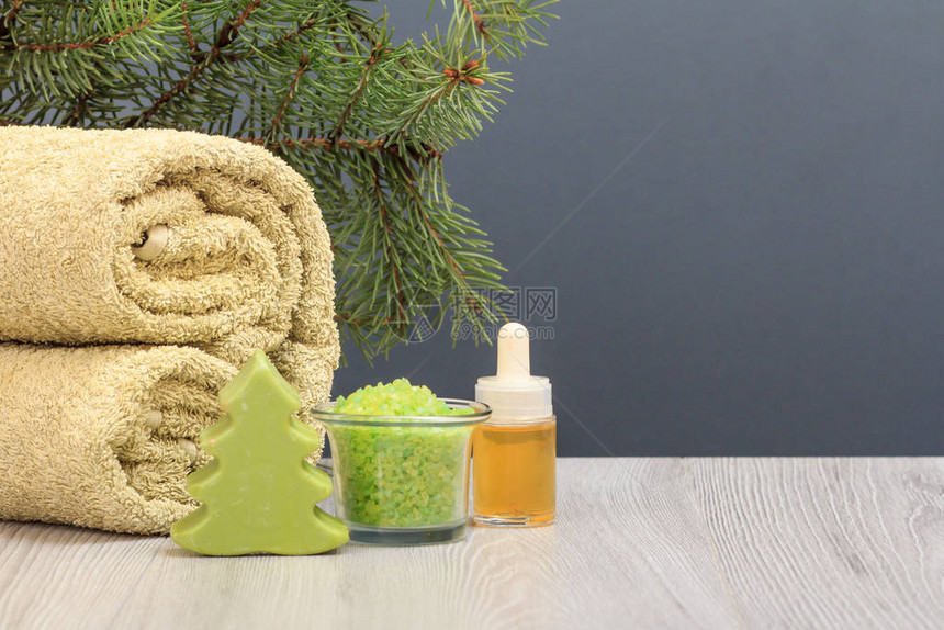 含有软毛巾肥皂海盐碗芳香油瓶和灰色背景的fir树枝图片