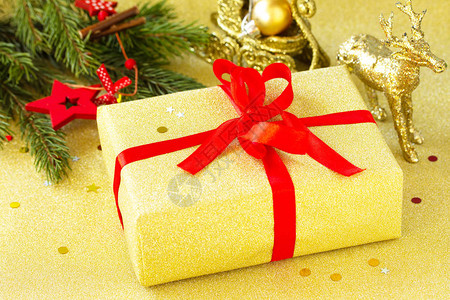 圣诞礼物盒配有红丝带和树枝装饰品的金盒图片