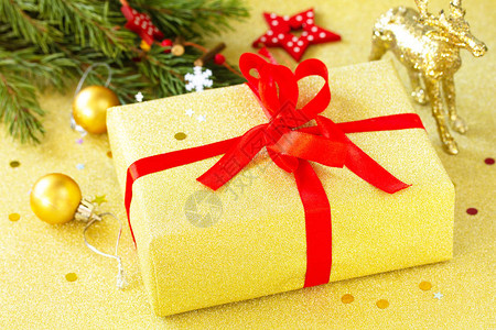 圣诞节赠送金盒配有红丝带和树枝装饰品图片