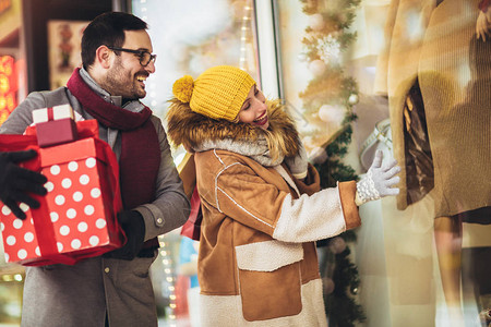 年轻夫妇在冬日购物窗户寻找圣诞礼图片