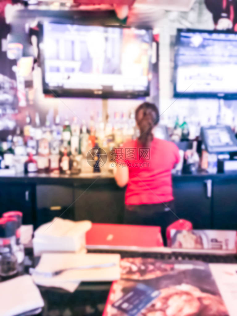 美国华盛顿州西雅图餐馆酒吧柜台穿红衬衫的女酒保运动模糊不清各种酒精饮料和挂起平板屏幕运动棒等图片