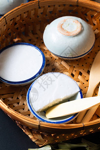 食品甜点概念泰式甜点KanomTuay椰子饭和潘丹蛋羹装在小瓷杯和黑色背景的竹篮中图片