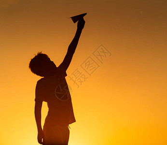 快乐的孩子在橙色日落时正在玩纸折飞机背景图片