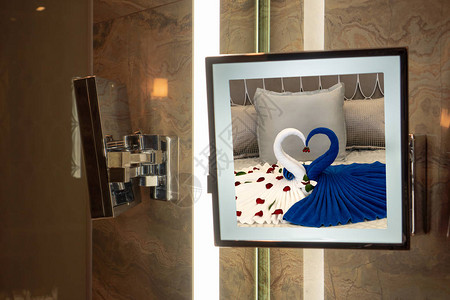在旅馆镜子中反射两只天鹅的床与亲人放松和在酒店度蜜月的概念图片
