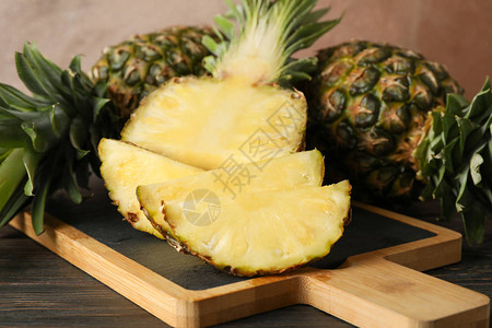 木制背景上带菠萝的切菜板特写图片