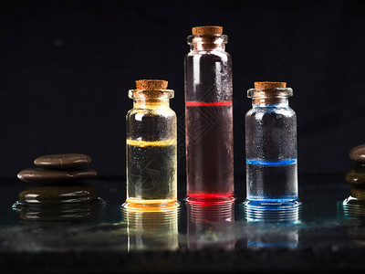 三个五颜六色的液体玻璃小瓶有医学研究的黑色背景图片