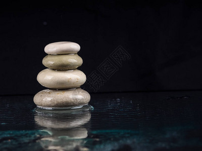 温泉石黑色闪亮的禅宗石头与水滴在黑色禅石堆在雨滴中背景图片