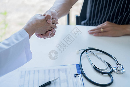 医生和病人握手医学合作只是亲手在桌子上摆图片