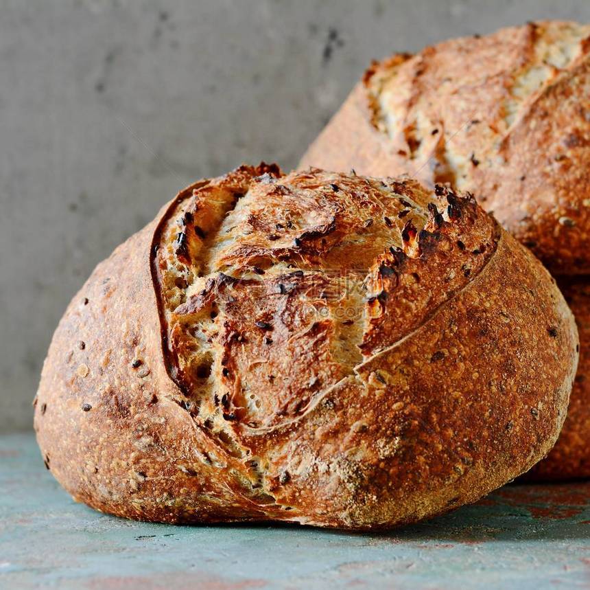 灰蓝色背景上由小麦和全麦面粉制成的自制新鲜出炉的乡村面包法国新图片
