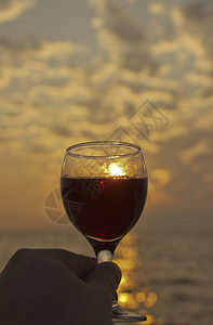 他手上的红酒杯日落时在海边浪漫的日子婚礼或情人节的庆祝活动的概图片