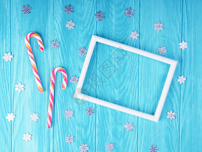 两个圣诞糖果手杖与蓝色木制背景上的框架图片