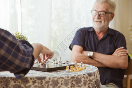 聪明的长老在家里玩象棋板游戏图片