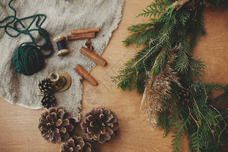 制作圣诞花环平躺木桌上的冷杉树枝松果线肉桂质朴的圣诞花环工作坊图片