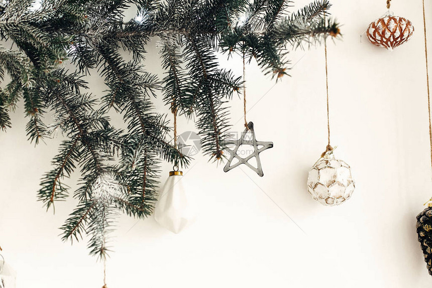 时尚的圣诞饰品挂在白墙上的冷杉树枝上创意圣诞节日装饰松枝与老式玻璃玩具斯堪的纳维图片