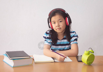 亚洲小女孩在写一本书和耳机听音图片